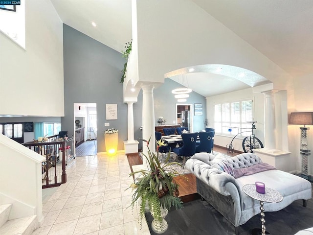 living room featuring light tile patterned floors, high vaulted ceiling, and decorative columns