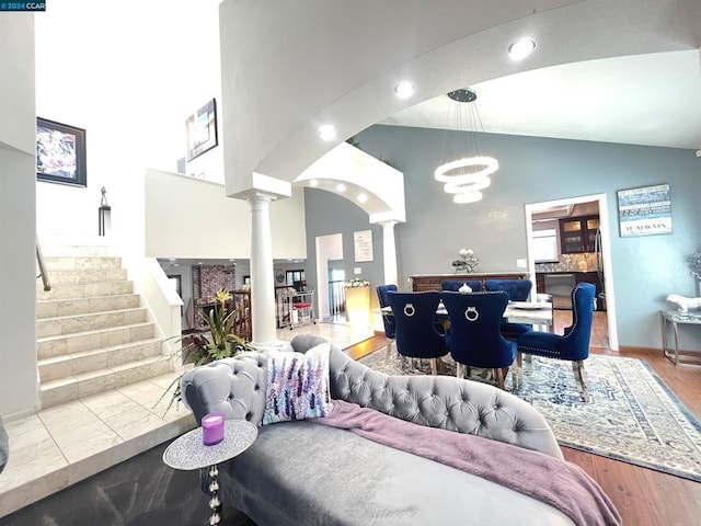 living room with high vaulted ceiling, ornate columns, and an inviting chandelier