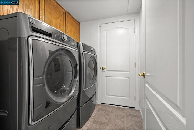 clothes washing area featuring washer and dryer and cabinets