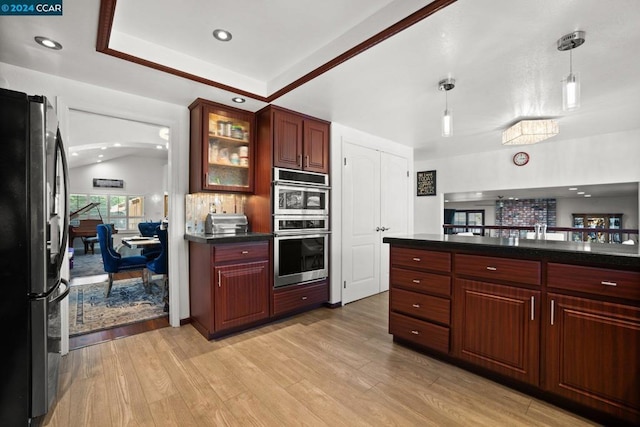 kitchen with appliances with stainless steel finishes, decorative backsplash, decorative light fixtures, vaulted ceiling, and light hardwood / wood-style flooring