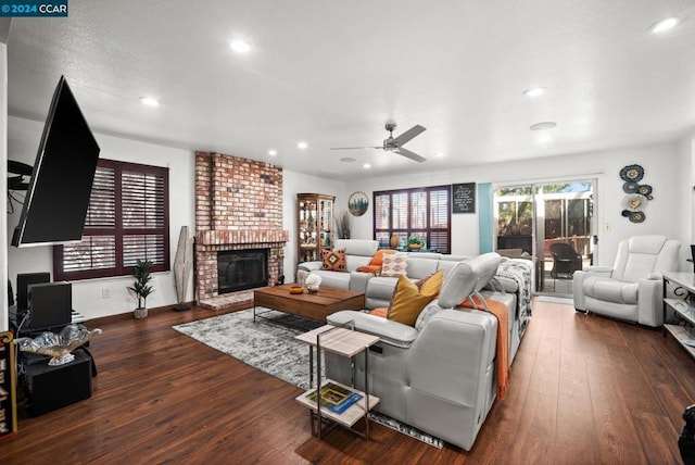 living room with a fireplace, ceiling fan, and dark wood-type flooring