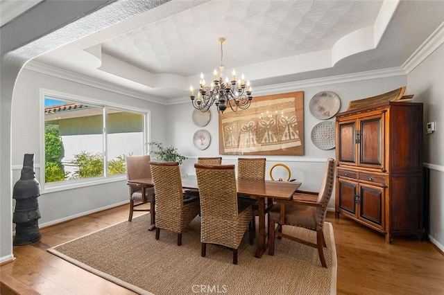 dining space featuring a chandelier, hardwood / wood-style floors, a tray ceiling, and ornamental molding