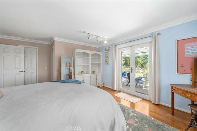 bedroom featuring rail lighting, access to outside, crown molding, light hardwood / wood-style flooring, and a closet