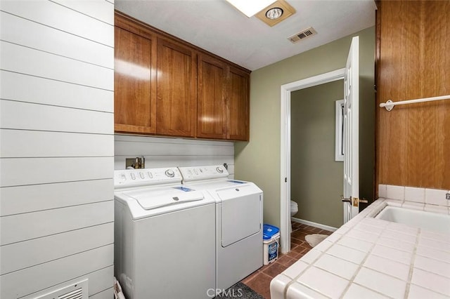 clothes washing area with washer and clothes dryer, dark tile patterned floors, cabinets, and sink