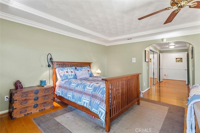 bedroom with ceiling fan, crown molding, and wood-type flooring