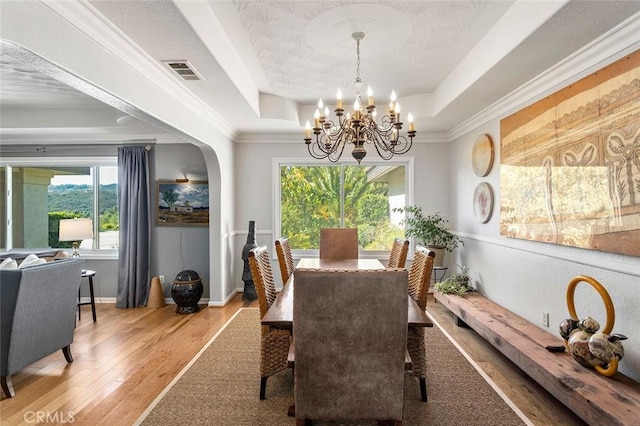 dining room featuring a tray ceiling, crown molding, hardwood / wood-style floors, and a chandelier