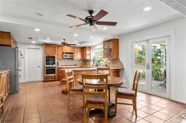 dining area with french doors, a textured ceiling, a raised ceiling, ceiling fan, and sink