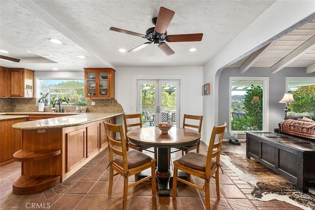 dining space with ceiling fan, french doors, sink, beamed ceiling, and a textured ceiling