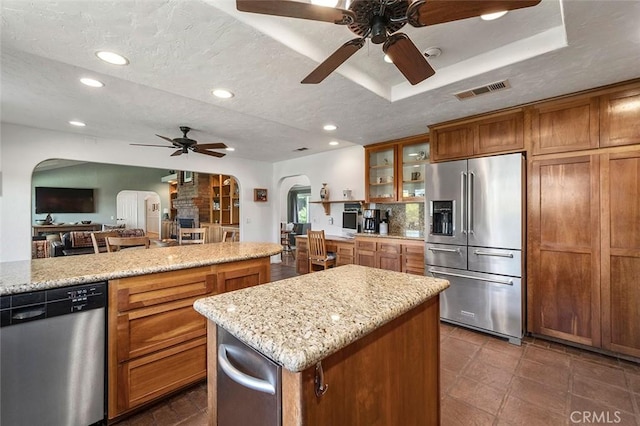 kitchen featuring light stone countertops, a textured ceiling, stainless steel appliances, and a kitchen island