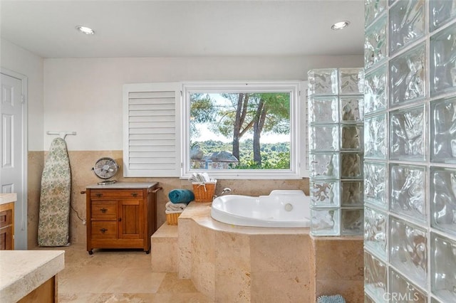 bathroom featuring tile patterned flooring, vanity, and tiled bath