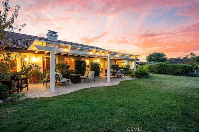 back house at dusk featuring a yard, a pergola, and a patio area