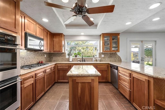 kitchen featuring kitchen peninsula, stainless steel appliances, tasteful backsplash, and a wealth of natural light