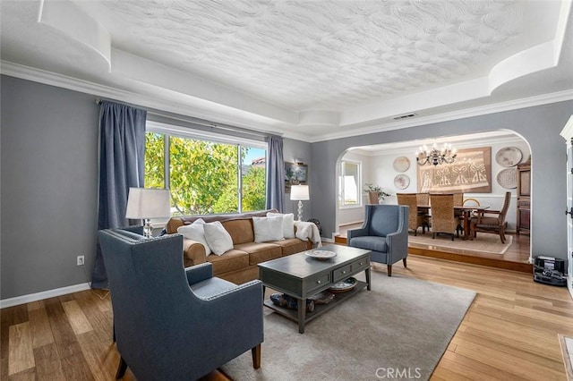 living room featuring a raised ceiling, light hardwood / wood-style flooring, and ornamental molding