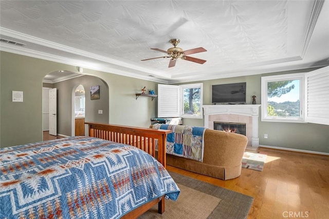 bedroom featuring hardwood / wood-style flooring, ceiling fan, a tile fireplace, and multiple windows