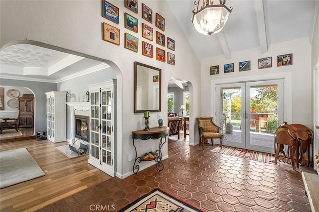 interior space with beam ceiling, french doors, an inviting chandelier, crown molding, and hardwood / wood-style floors