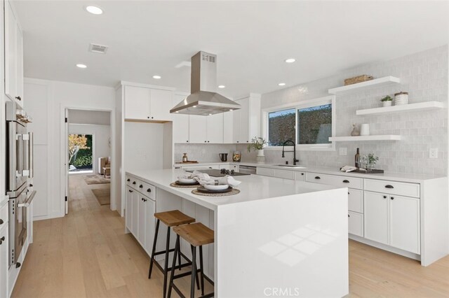 kitchen featuring sink, white cabinetry, island exhaust hood, and a kitchen island