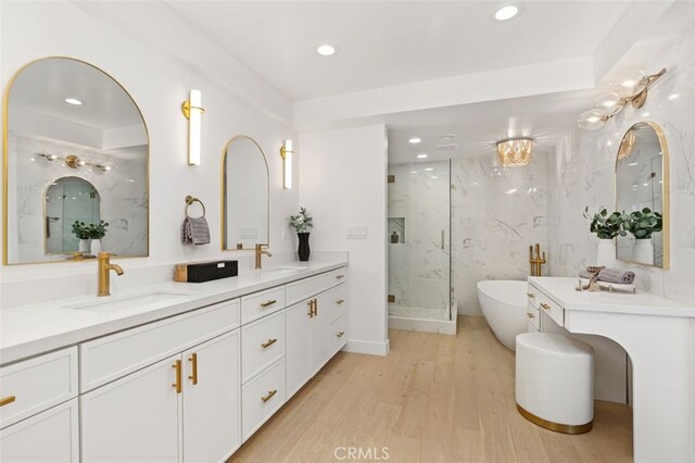 bathroom with wood-type flooring, vanity, and shower with separate bathtub