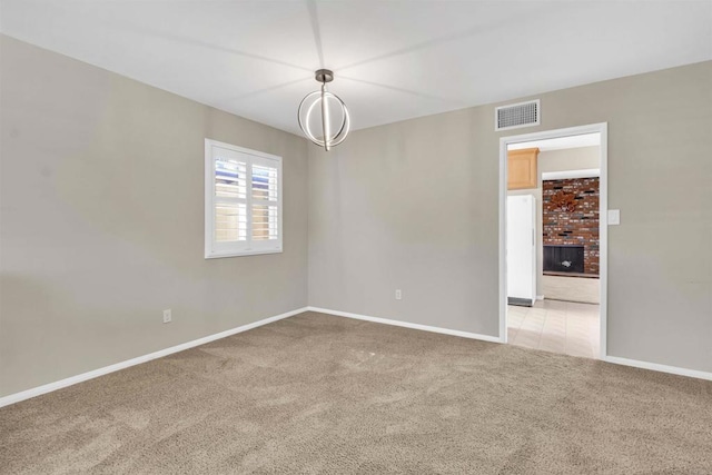 carpeted spare room with a fireplace and a chandelier