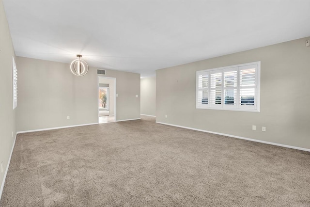 unfurnished room with carpet, plenty of natural light, and an inviting chandelier