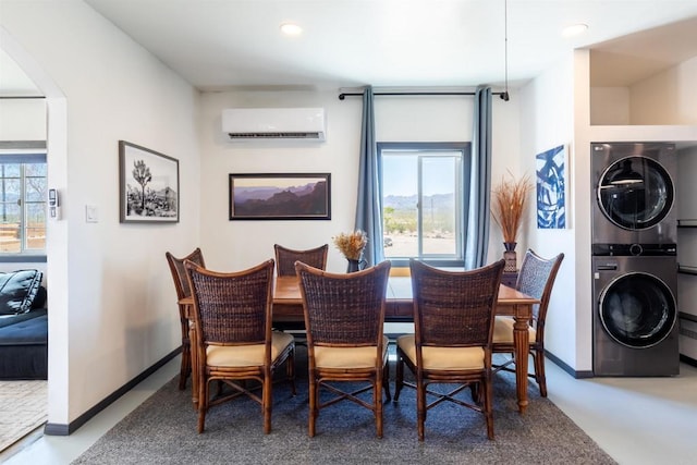 dining room featuring concrete flooring, an AC wall unit, and stacked washer / dryer