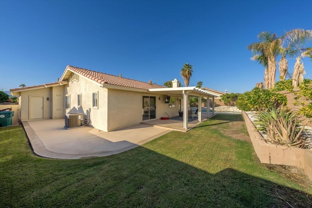 rear view of house with a lawn, cooling unit, and a patio