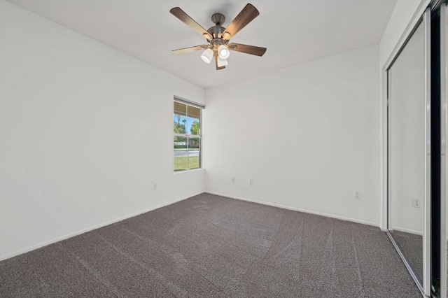 unfurnished bedroom featuring ceiling fan, a closet, and dark carpet