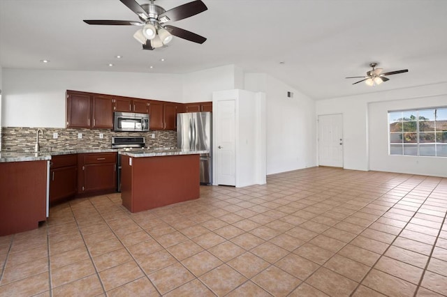 kitchen featuring backsplash, stainless steel appliances, vaulted ceiling, ceiling fan, and a center island