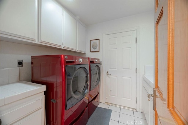 clothes washing area with cabinets, light tile patterned floors, and washer and dryer