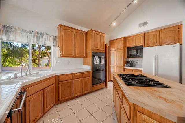 kitchen featuring a center island, backsplash, black appliances, vaulted ceiling, and light tile patterned floors