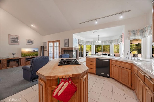 kitchen featuring dishwasher, a center island, lofted ceiling, stainless steel gas stovetop, and light tile patterned floors