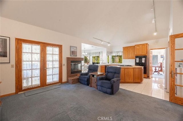 carpeted living room with french doors, track lighting, and a brick fireplace