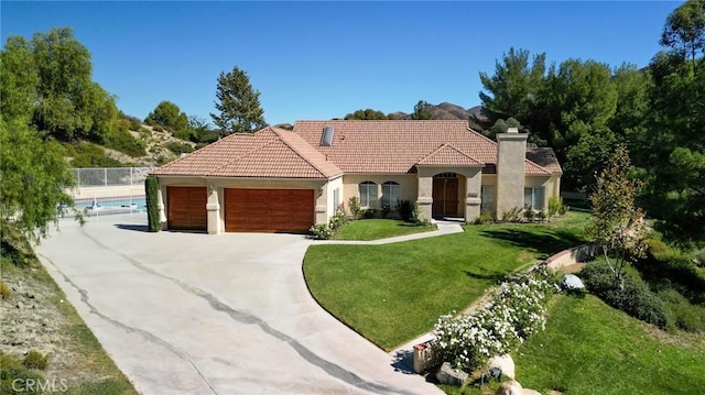 mediterranean / spanish-style home with a garage, a fenced in pool, and a front lawn