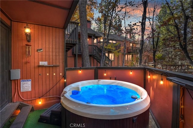 pool at dusk featuring a hot tub