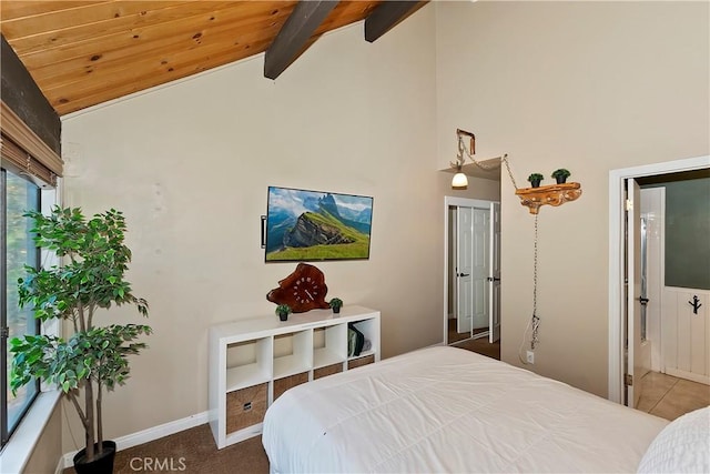 bedroom with carpet, beam ceiling, high vaulted ceiling, and ensuite bath