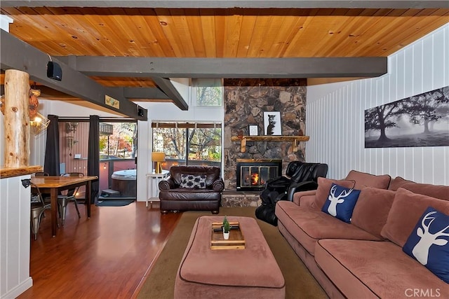 living room with beam ceiling, a stone fireplace, hardwood / wood-style floors, and wooden ceiling