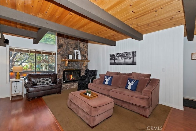 living room featuring beam ceiling, hardwood / wood-style flooring, a stone fireplace, and wood ceiling