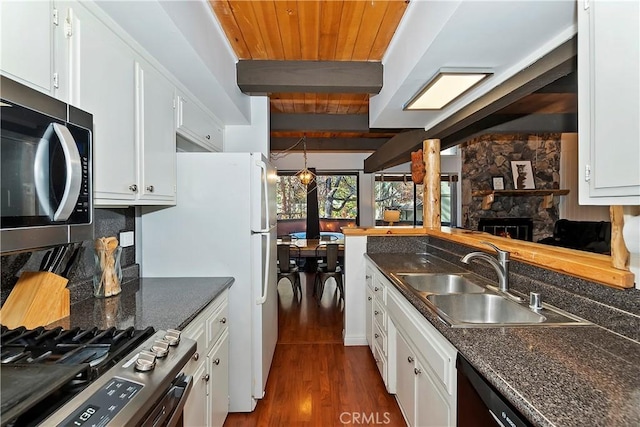 kitchen featuring beamed ceiling, appliances with stainless steel finishes, white cabinetry, and sink