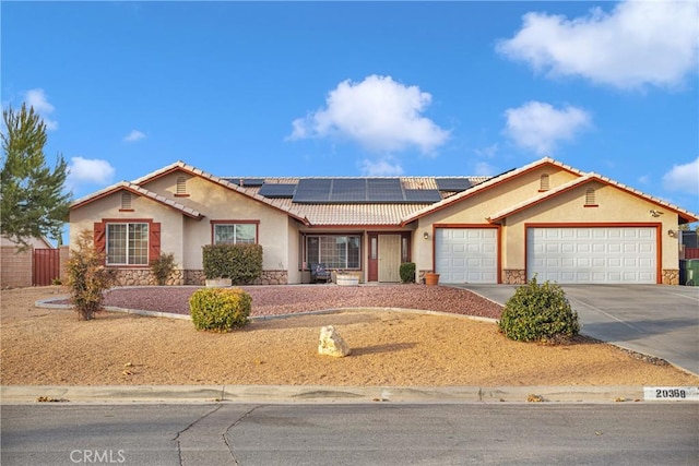 ranch-style house featuring a garage and solar panels