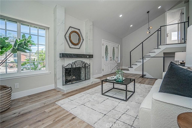 living room with a fireplace, light hardwood / wood-style floors, and lofted ceiling