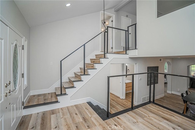 foyer entrance with vaulted ceiling with beams and light hardwood / wood-style floors