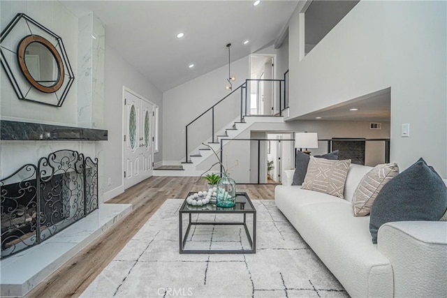 living room with light wood-type flooring and high vaulted ceiling