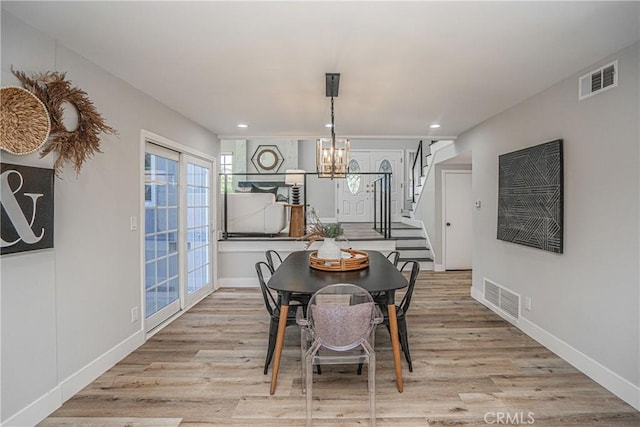 dining space with a notable chandelier and light hardwood / wood-style flooring