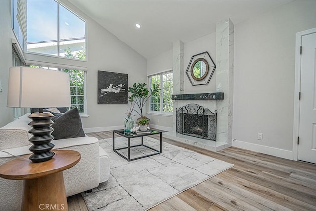 living room featuring high vaulted ceiling, wood-type flooring, and a tile fireplace