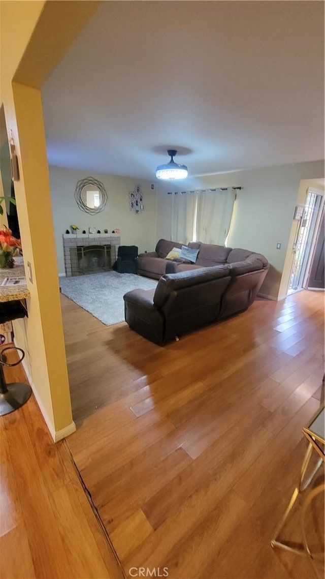 living room with hardwood / wood-style flooring and a brick fireplace