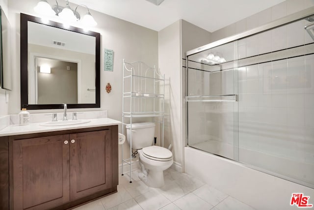 full bathroom featuring tile patterned flooring, vanity, toilet, and bath / shower combo with glass door