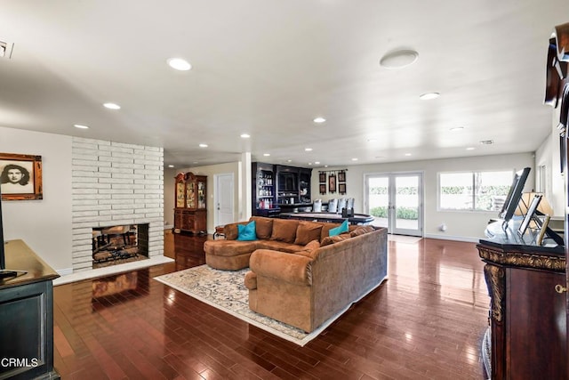 living room featuring french doors, dark hardwood / wood-style flooring, and a brick fireplace