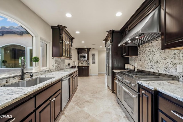 kitchen featuring dark brown cabinetry, sink, wall chimney exhaust hood, and appliances with stainless steel finishes