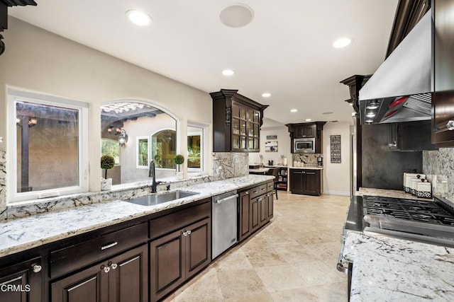 kitchen with wall chimney exhaust hood, decorative backsplash, sink, and appliances with stainless steel finishes