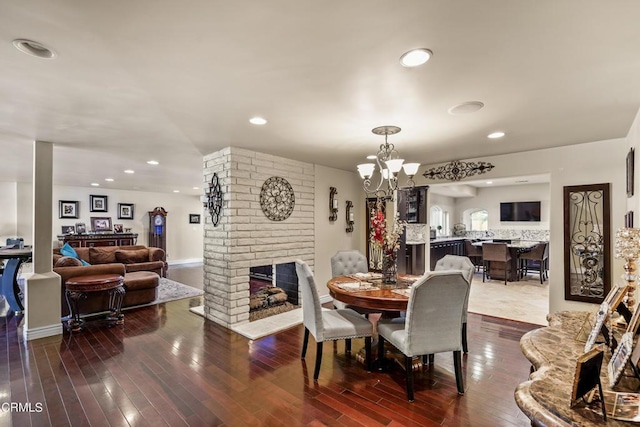 dining area featuring hardwood / wood-style floors, a notable chandelier, and a brick fireplace