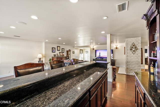 kitchen featuring dark hardwood / wood-style floors, dark brown cabinets, billiards, and dark stone counters